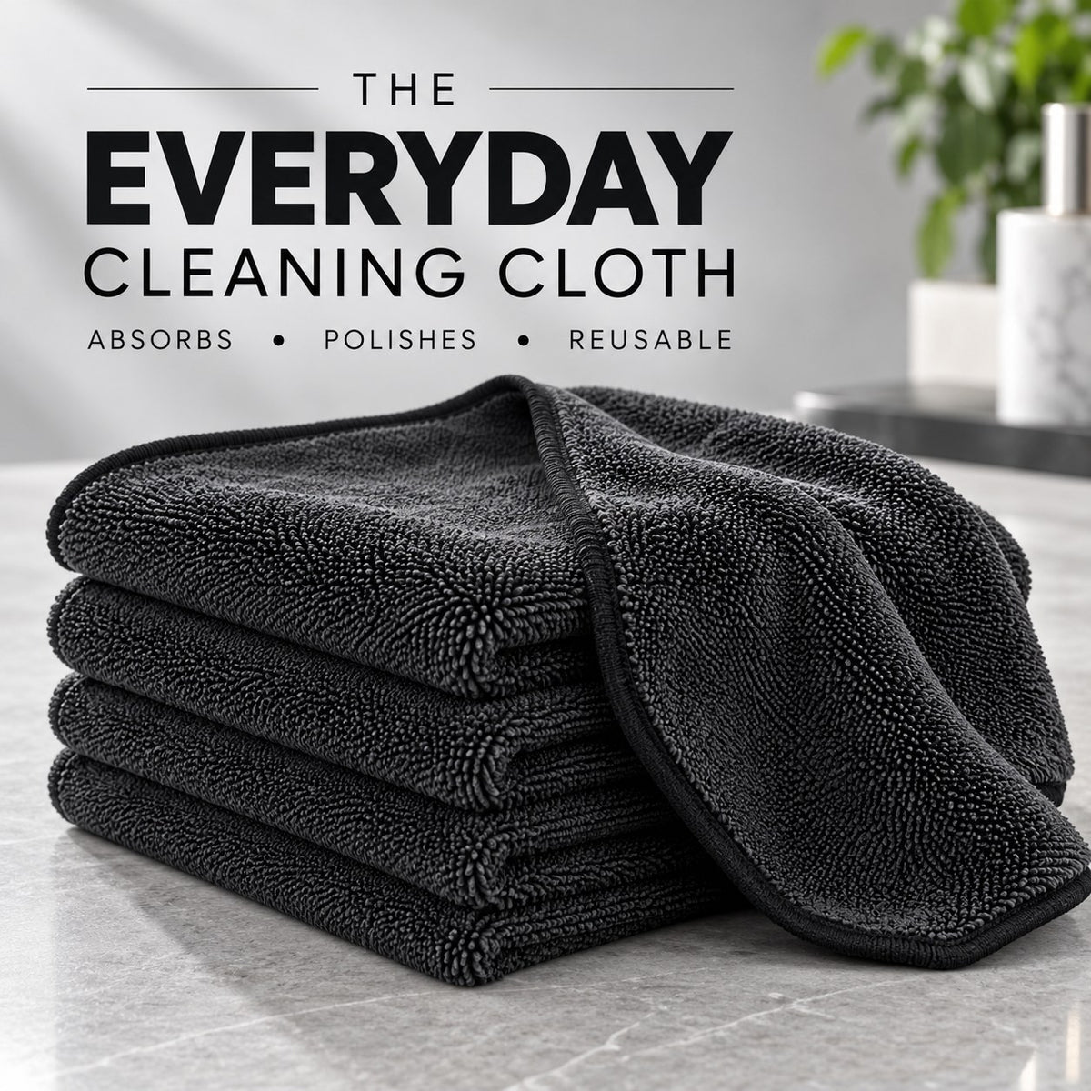 Stack of folded black EzyClean microfiber cleaning cloths on a marble counter